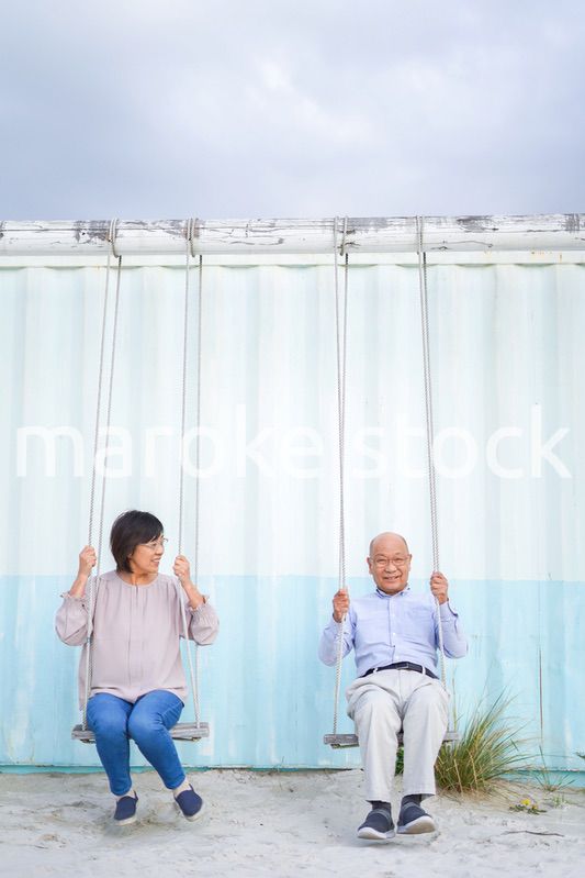 夫婦でブランコに乗るシニア