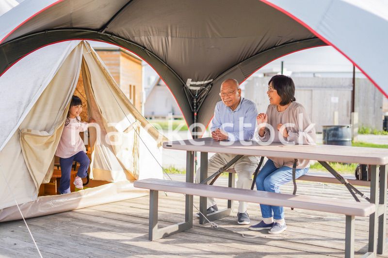 孫とキャンプをする高齢の夫婦