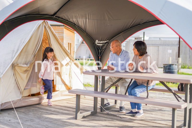 孫とキャンプをする高齢の夫婦