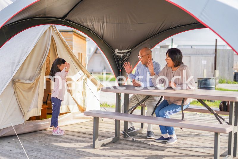 孫とキャンプをする高齢の夫婦