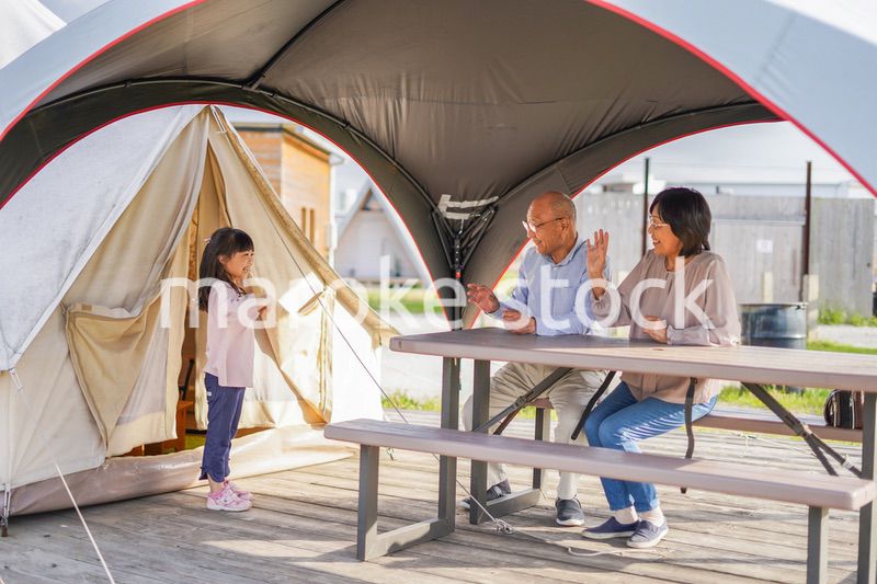 孫とキャンプをする高齢の夫婦