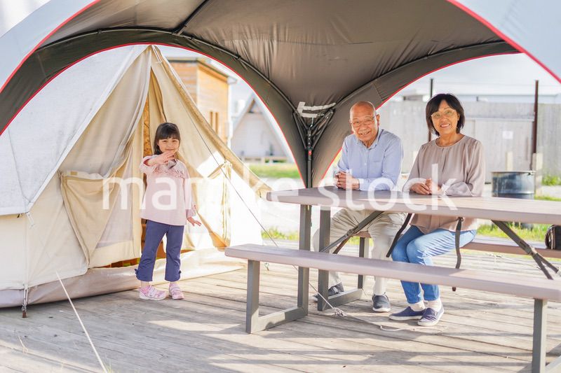孫とキャンプをする高齢の夫婦