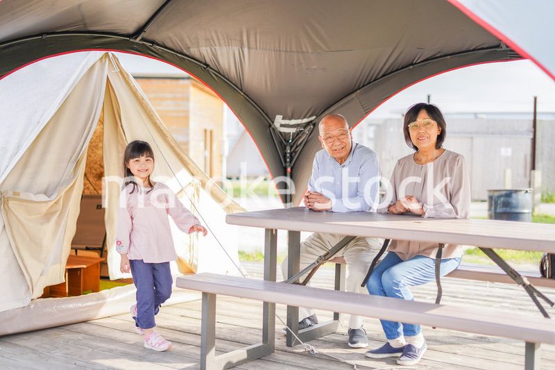 孫とキャンプをする高齢の夫婦