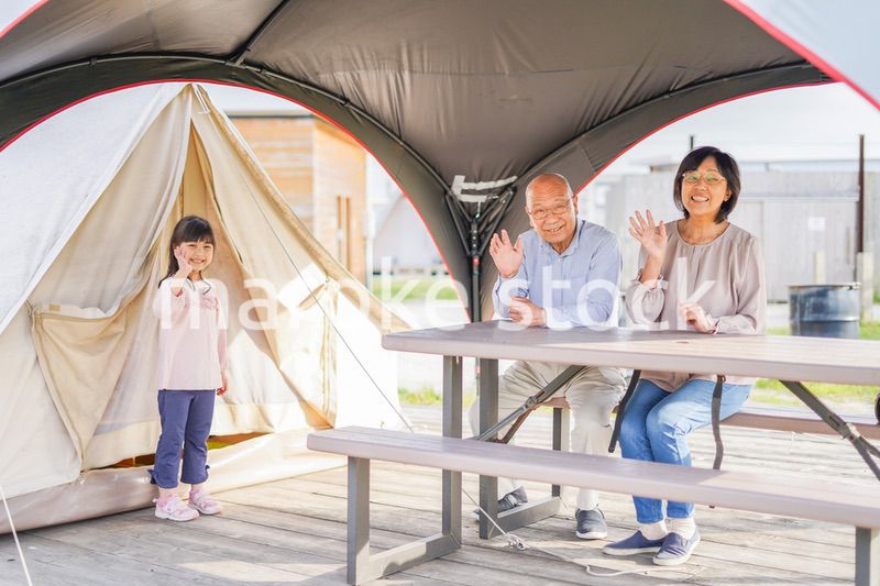 孫とキャンプをする高齢の夫婦