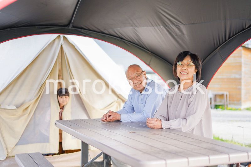 孫とキャンプをする高齢の夫婦