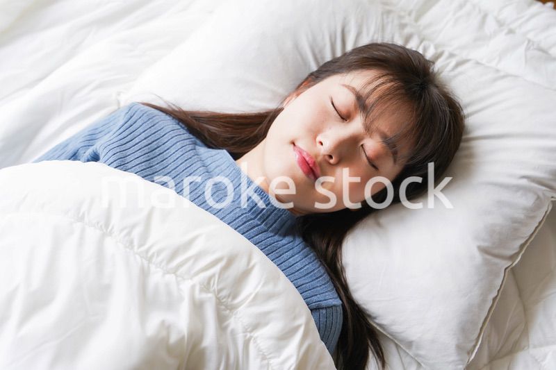 布団に入って睡眠を取る若い女性