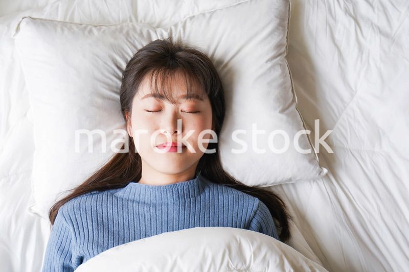 布団に入って睡眠を取る若い女性