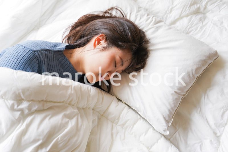 布団に入って睡眠を取る若い女性