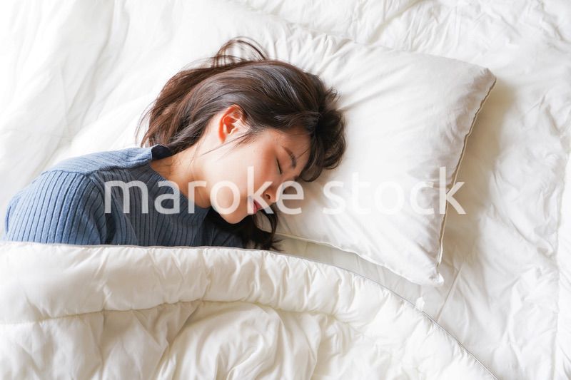 布団に入って睡眠を取る若い女性