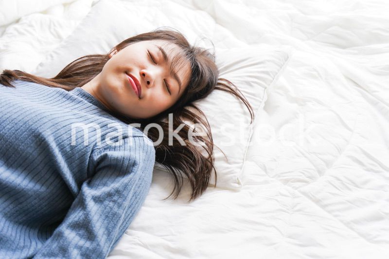 布団に入って睡眠を取る若い女性