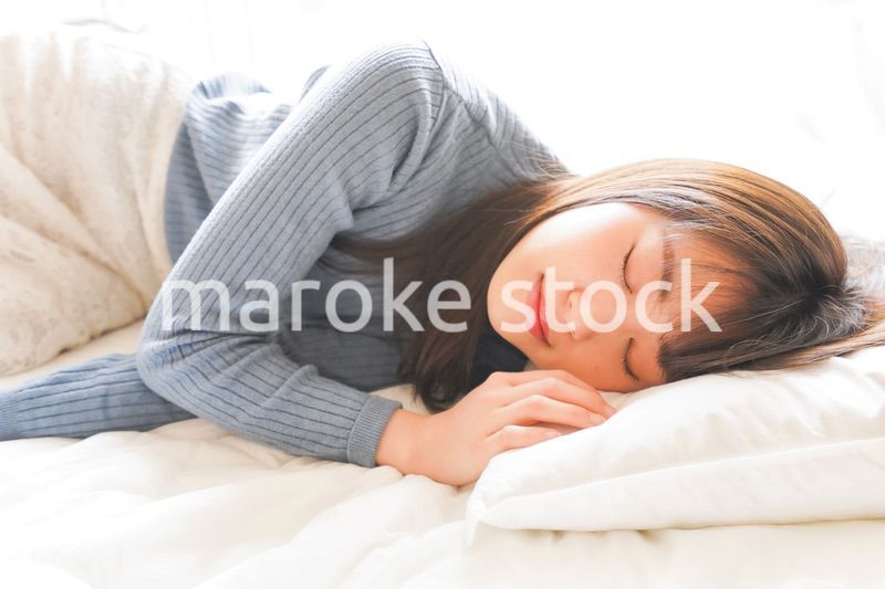布団に入って睡眠を取る若い女性