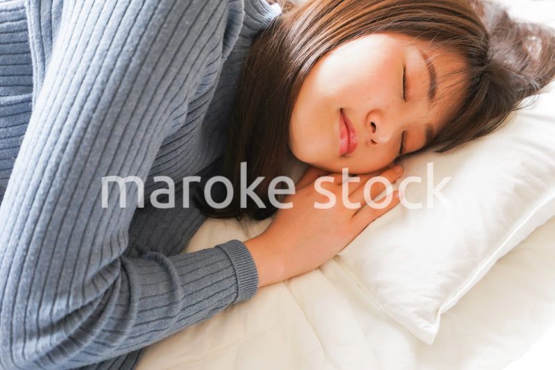 布団に入って睡眠を取る若い女性