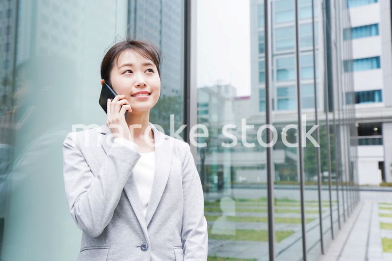 オフィス街で電話をする若いビジネスウーマン