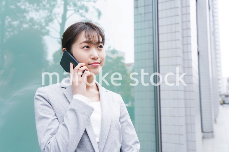 オフィス街で電話をする若いビジネスウーマン