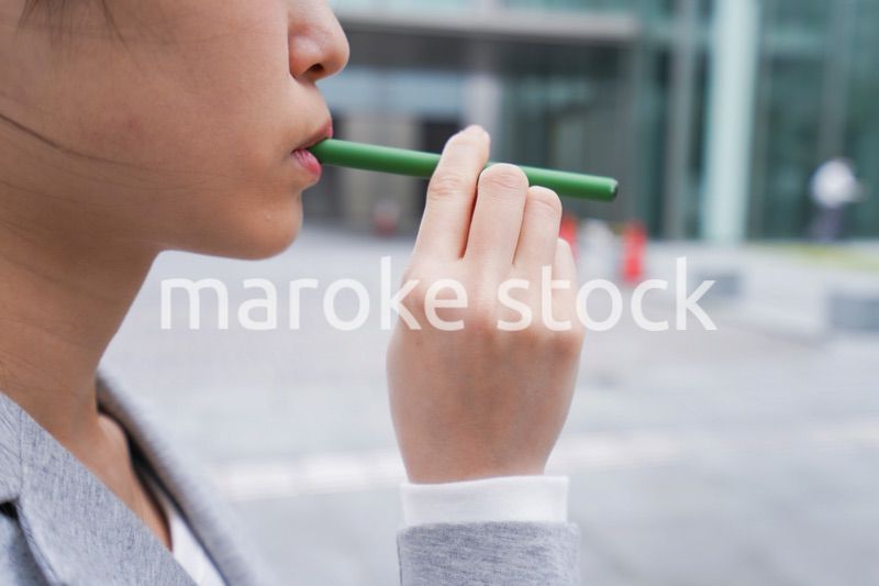 電子タバコを吸う若いビジネスウーマン