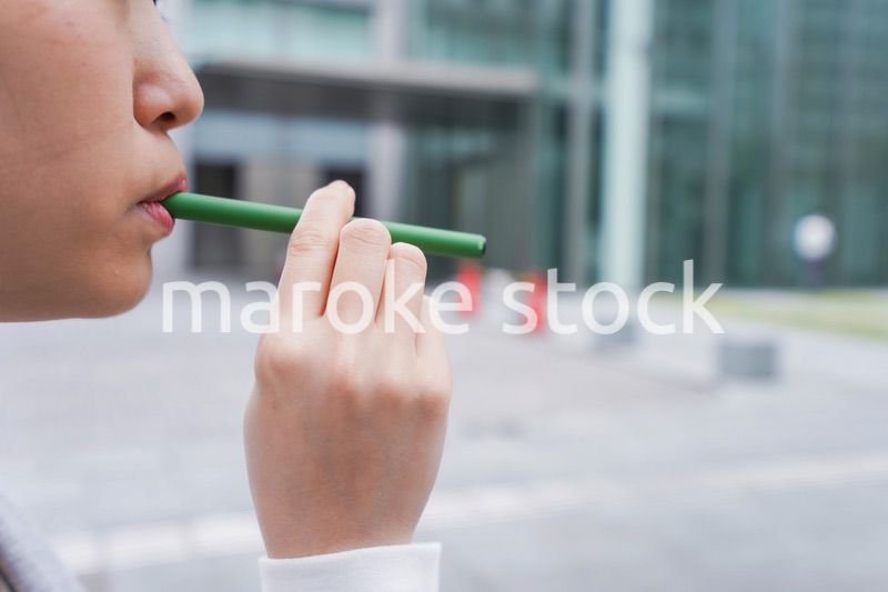 電子タバコを吸う若いビジネスウーマン