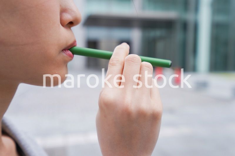 電子タバコを吸う若いビジネスウーマン