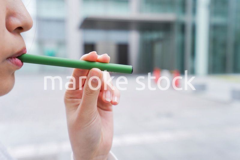 電子タバコを吸う若いビジネスウーマン