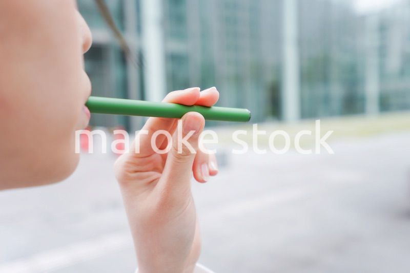 電子タバコを吸う若いビジネスウーマン