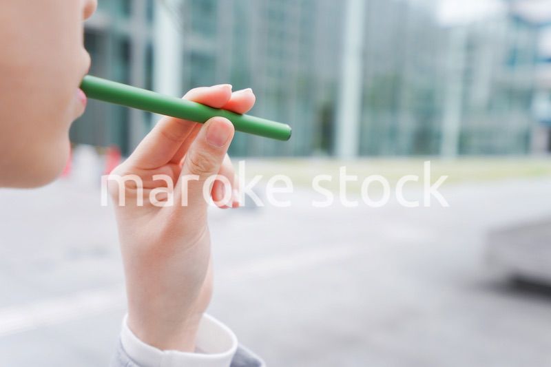 電子タバコを吸う若いビジネスウーマン