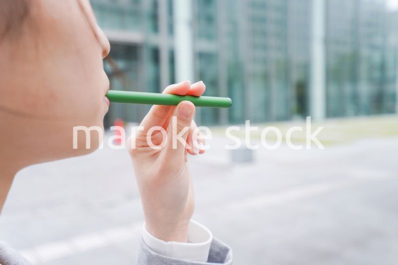 電子タバコを吸う若いビジネスウーマン