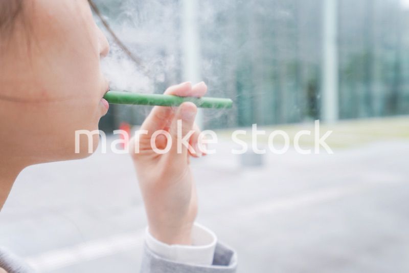 電子タバコを吸う若いビジネスウーマン