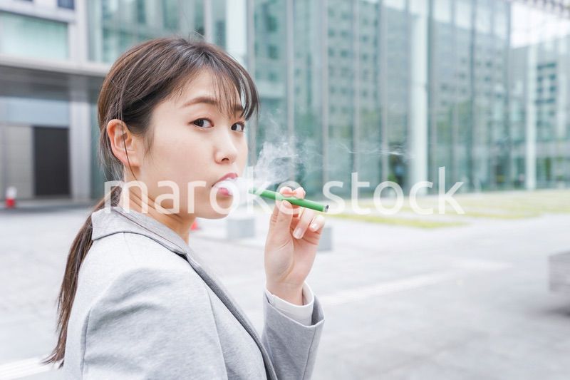 電子タバコを吸う若いビジネスウーマン