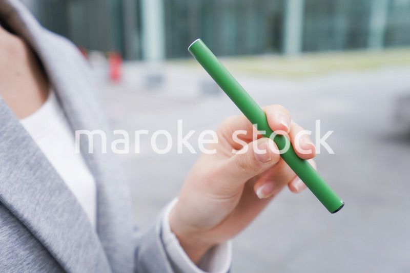 電子タバコを吸う若いビジネスウーマン