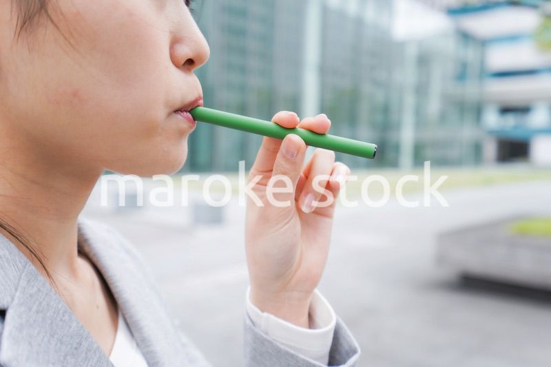 電子タバコを吸う若いビジネスウーマン
