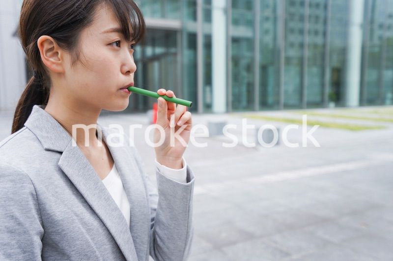 電子タバコを吸う若いビジネスウーマン