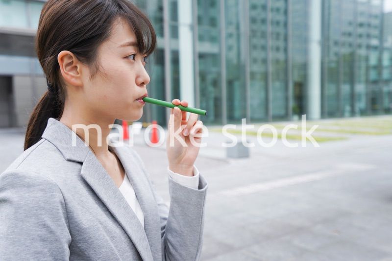 電子タバコを吸う若いビジネスウーマン