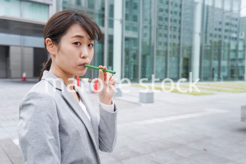 電子タバコを吸う若いビジネスウーマン