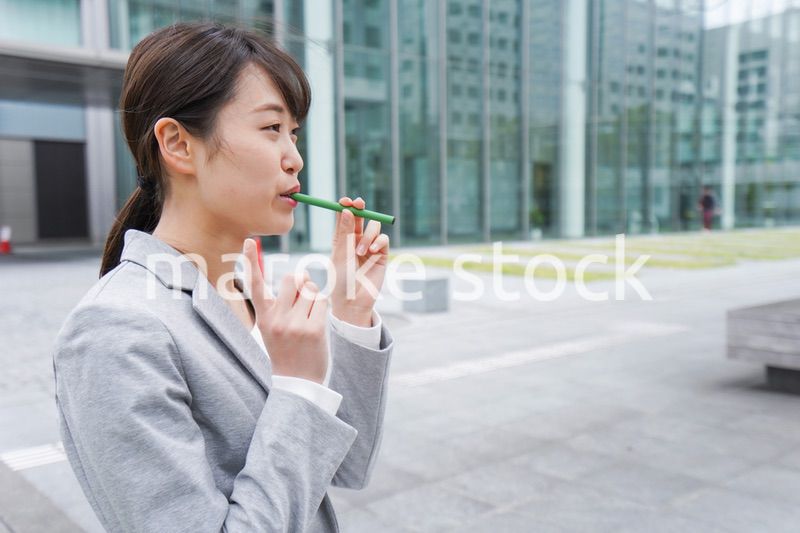 電子タバコを吸う若いビジネスウーマン