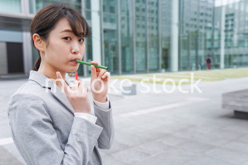電子タバコを吸う若いビジネスウーマン