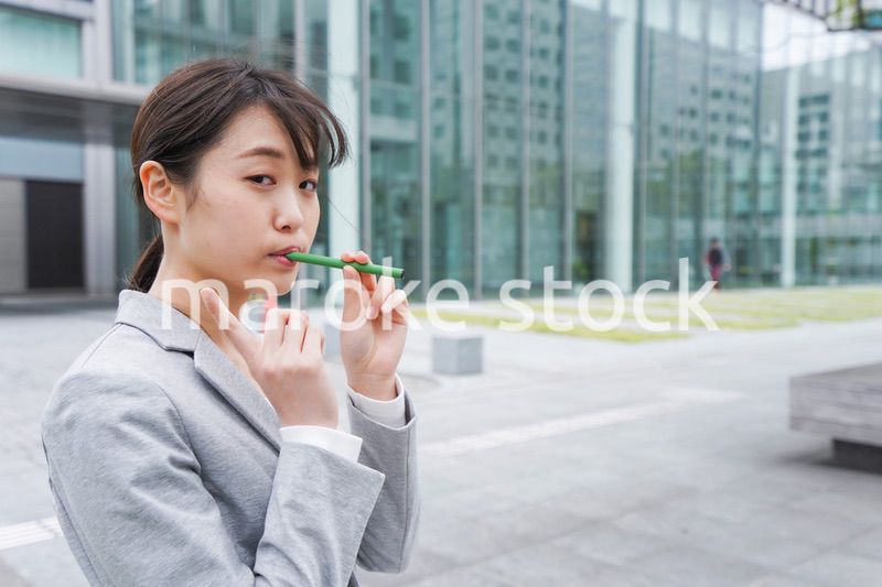 電子タバコを吸う若いビジネスウーマン