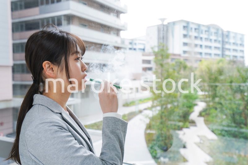 電子タバコを吸う若いビジネスウーマン