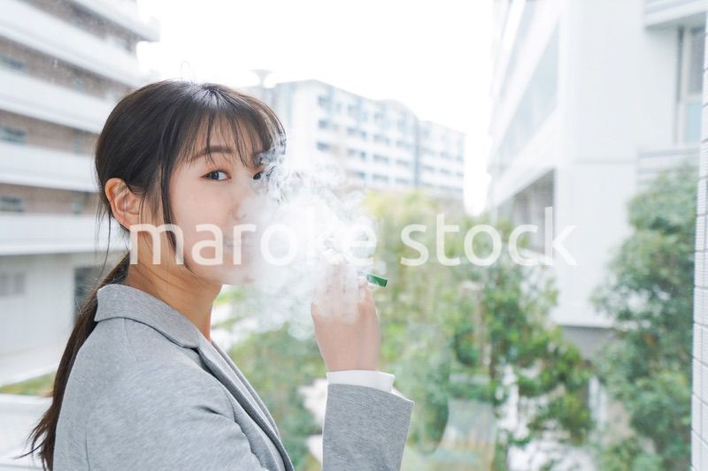 電子タバコを吸う若いビジネスウーマン
