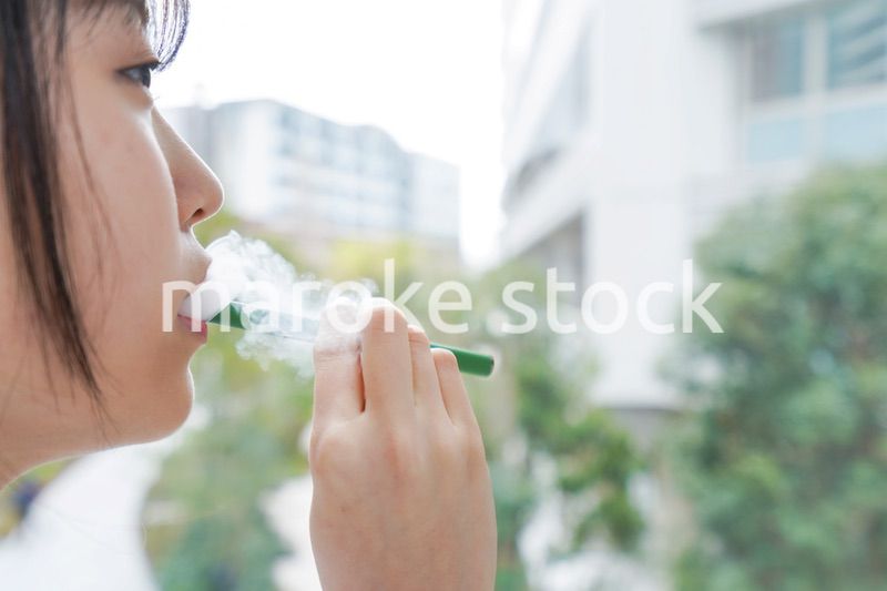 電子タバコを吸う若いビジネスウーマン