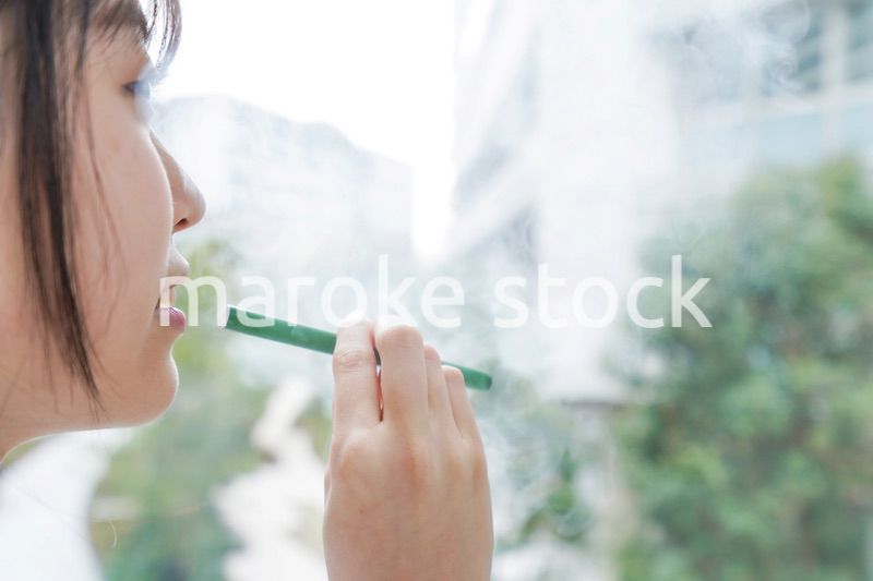 電子タバコを吸う若いビジネスウーマン