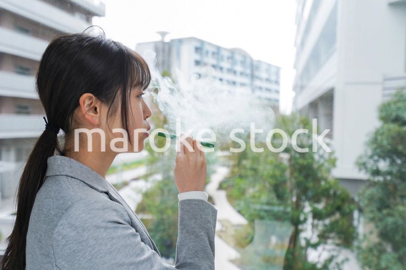 電子タバコを吸う若いビジネスウーマン