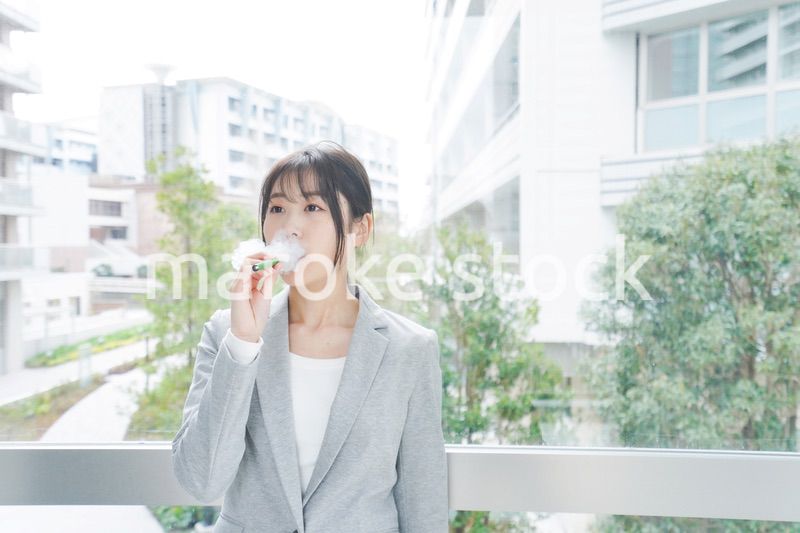 電子タバコを吸う若いビジネスウーマン