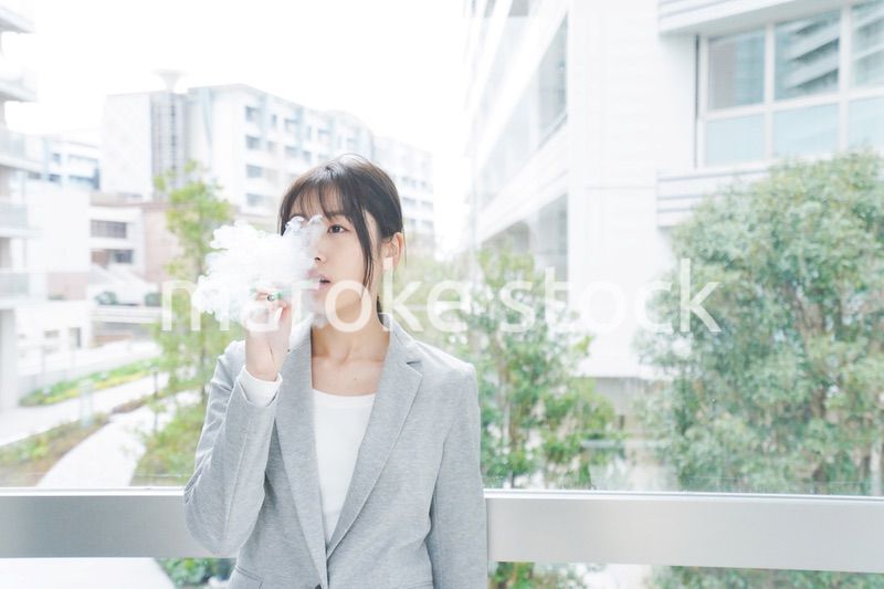 電子タバコを吸う若いビジネスウーマン