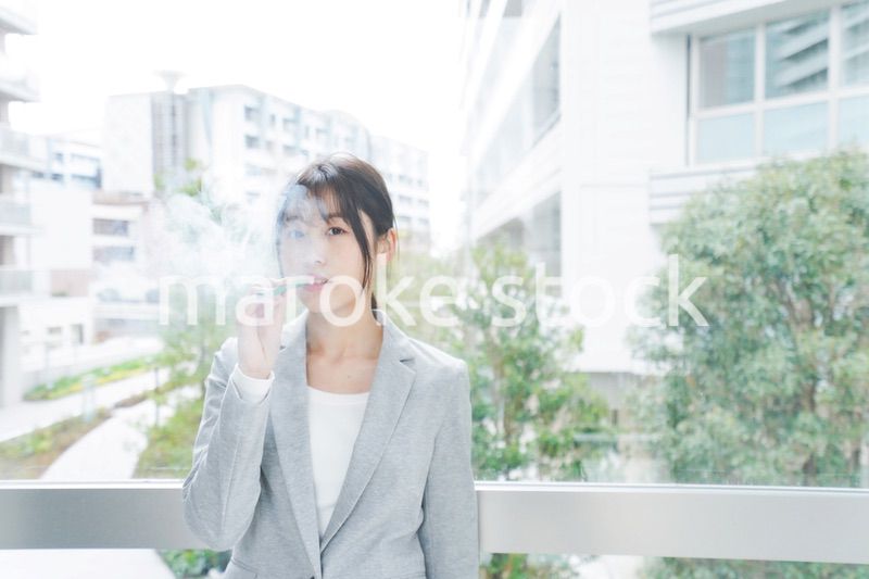 電子タバコを吸う若いビジネスウーマン