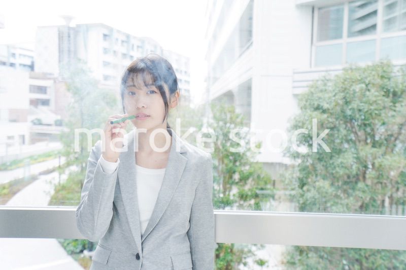 電子タバコを吸う若いビジネスウーマン