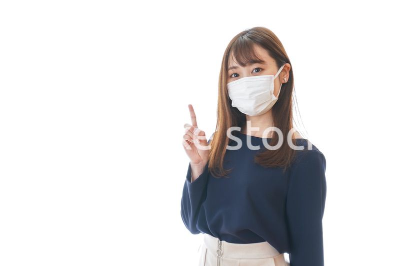 マスクを装着して指を指す若い女性