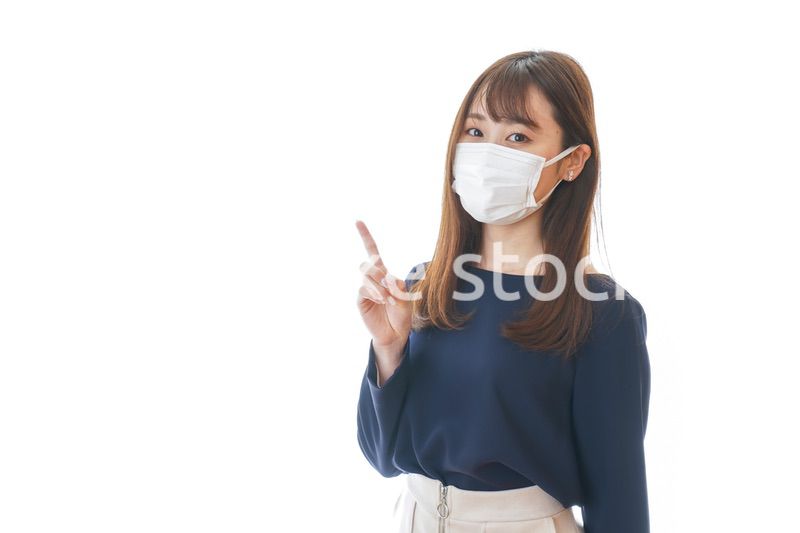 マスクを装着して指を指す若い女性