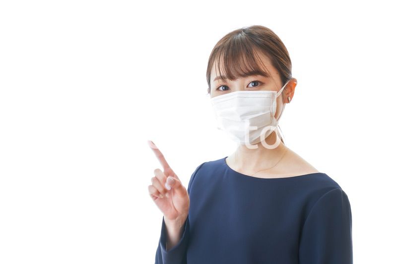 マスクを装着して指を指す若い女性