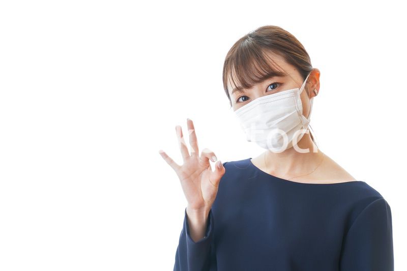 マスクを装着してOKサインをする若い女性