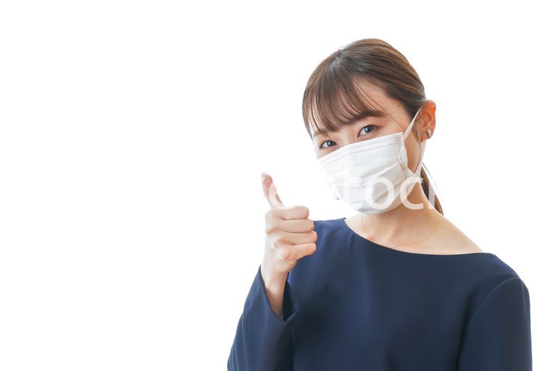 マスクを装着して指を指す若い女性