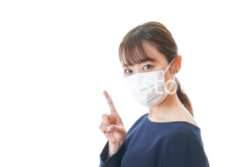 マスクを装着して指を指す若い女性